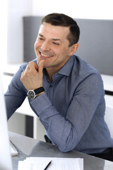 Businessman working with computer in modern office. Headshot of male entrepreneur or company director at workplace. Business concept