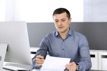 Businessman working with computer in modern office. Headshot of male entrepreneur or company...