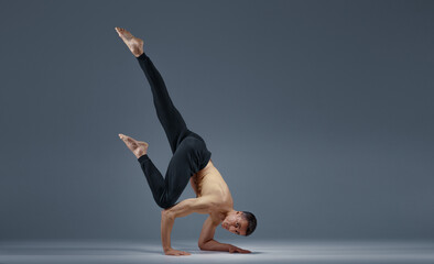 Male yoga keeps balanc in difficult pose on hands