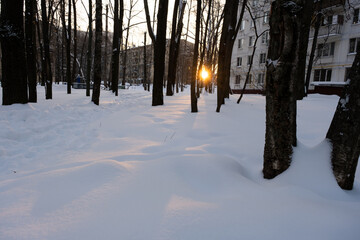A ray of light breaks into the snow. City in the snow. Sunset in the city. Winter in the city. Snowy day.