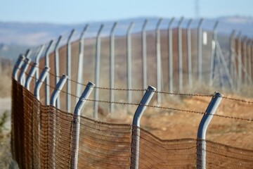 Perspective view of a fence with barbed wire in the field