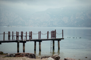 boat pier on Lake Garda in the early morning. Pier on the lake in foggy weather. Malcesine, Lake Garda, Italy