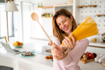 Portrait of beautiful woman with pasta at her kitchen, preparing to cook