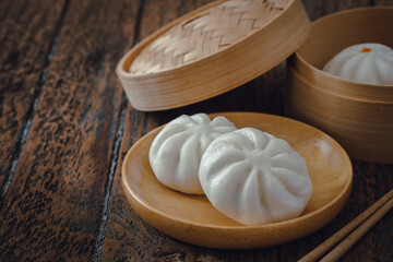 Steamed pork buns on wooden plate, Chinese dim sum .