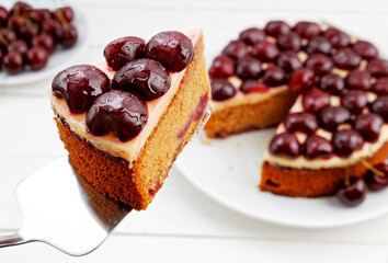 Closeup piece of homemade cake with cherries against blurred background of table. Shallow focus