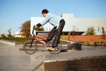 Young bmx biker doing trick, training in skatepark