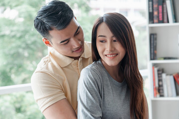 Happy couple sitting on the sofa and being a man teases his girlfriend with love in the living room and relax. Concept of romantic on valentine day. Proposal and marriage