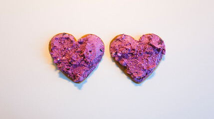 Fototapeta premium Two heart shaped cookies spread with blueberry curd raw cream for Valentine's Day on white table surface top view, Homemade sweet dessert