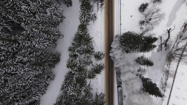 Old train Mocanita with big smoke during winter time in Moldovita, Bucovina. Romania. Filmed from above with drone.