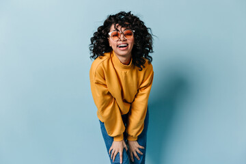 Laughing woman in sunglasses looking at camera. Front view of good-humoured girl in yellow...