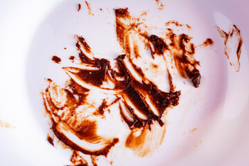 Close up view of dirty white plate eaten chocolate sauce stain. Finished chocolate cake. Concept of...