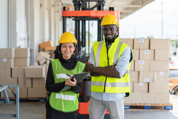 Young Asian woman with man worker in safety vest and yellow helmet working at shipment at warehouse...