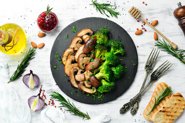 Organic food. Fried mushrooms and broccoli on a black stone plate. Rustic style. Top view.