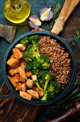 Dietary food. Boiled buckwheat, chicken fillet and broccoli in a black pan. Rustic style. Top view.