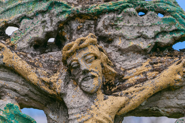 Ancient stone sculpture of Jesus Christ, crucified on a cross