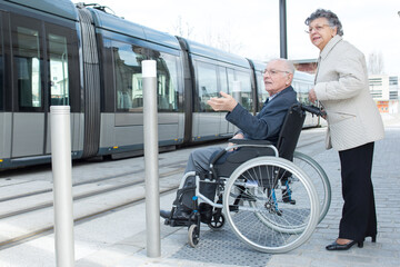 elderly couple waiting to board tram man in wheelchair