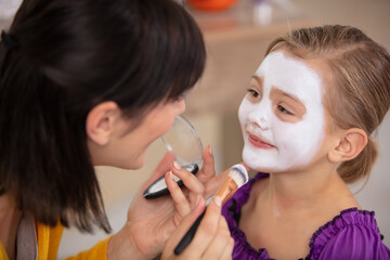 mum applies face paint to daughters face