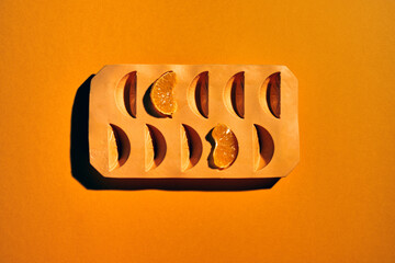 Overhead shot of a container with orange segments on a flat orange background .