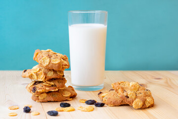 Group of freshly baked biscuits with cereal and raisins and glass of milk on blue background. Concept of healthy snack and tasty breakfast.