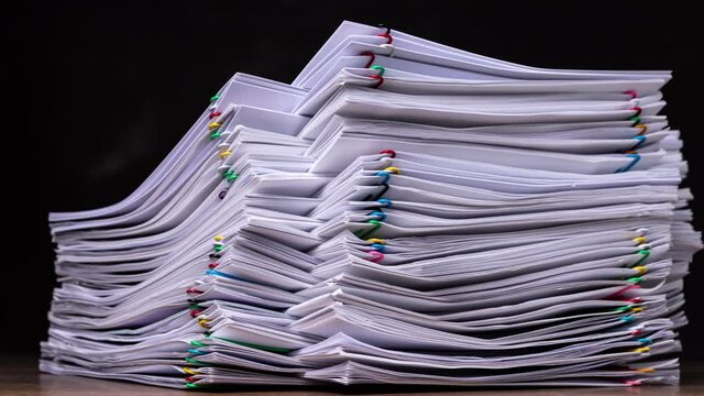 4K Stop motion of close-up stack overload document report paper with paperclip place increases and decrease on black background, business and education concept. 
