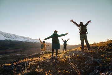 Happy hikers with raised arms in sunset mountains