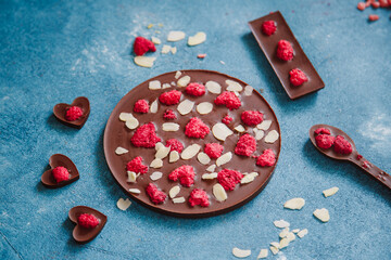 Diet dark chocolate without sugar based on cocoa and stevia with the addition of freeze-dried berries, nuts and fruits. Top view on blue background