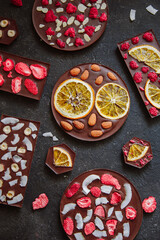 Diet dark chocolate without sugar based on cocoa and stevia with the addition of freeze-dried berries, nuts and fruits. Top view on black background