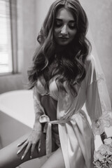 The bride is in the bathroom. Morning of the bride. White wedding bouquet in hands. Black and white photo.
