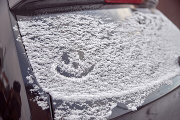 Smile made from snow on a car glass