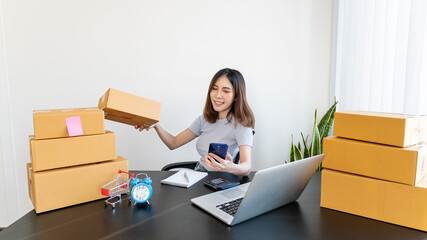 Young Asian women carry their own business phones and boxes on online shopping at home packaging is a popular business SME online shopping.