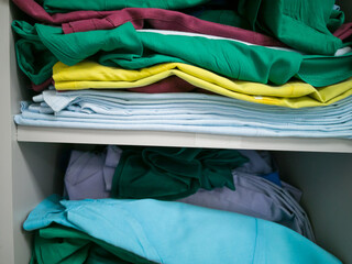 Colorful stacks of folded clothes on shelfs.