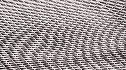 Abstract, monochrome background image of mettalic lattice viewed under the angle. Shallow depth of field.