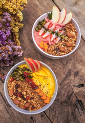 Healthy pineapple, mango and strawberry smoothie bowl with granola, seeds , almond fresh strawberries and fresh apple in White ceramic bowl.detox, vegetarian, vegan food concept 