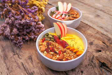 Healthy pineapple, mango and strawberry smoothie bowl with granola, seeds , almond fresh strawberries and fresh apple in White ceramic bowl.detox, vegetarian, vegan food concept 