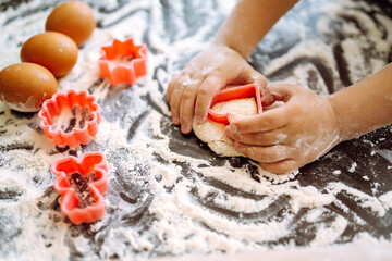 Close up of boy hands carving dough with cookie heart cutters. Easter baking preparation. A little chef carves ginger Cookies.
