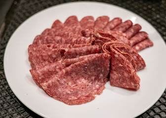 Fresh homemade salami on white plate.