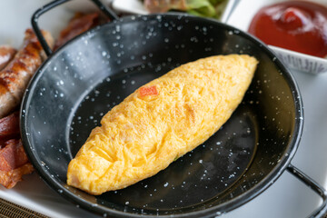 Classic western breakfast plate with omelette, sausages and bacons.