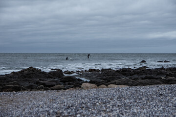 Fototapeta na wymiar surf y rocas en la orilla en día de tormenta