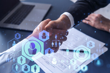 Recruitment concept to hiring of a new talented specialists for international company. Handshake to sign in of employment agreement. Social media hologram icons over the table with documents.