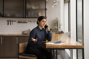 Busy indian female consultant give recommendation to client by cell reading documents opened on...