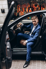 Portrait of the groom driving a black limousine. The groom is preparing to meet the bride.