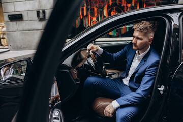 Portrait of the groom driving a black limousine. The groom is preparing to meet the bride.