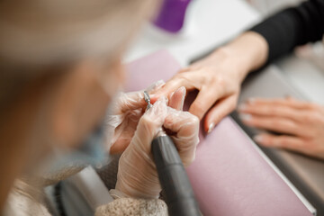 Obraz na płótnie Canvas Professional manicure master is doing nails for happy client in beauty salon