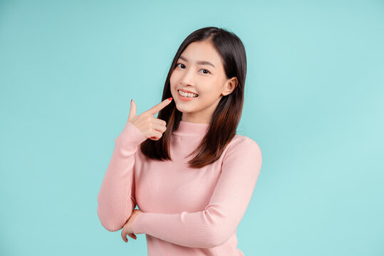 Dental braces of young asian woman wearing retainer braces glad emotion with white teeth increase confidence for healthy on blue background isolated, Happiness teenager smiling facial expression.