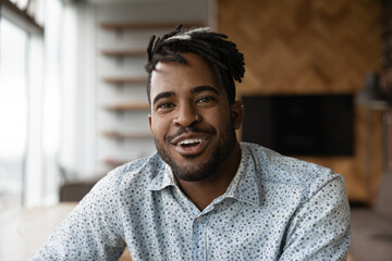 Headshot portrait of positive smiling young black man hipster looking at camera webcam talk by...