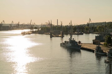 Port of Gdynia at sunset. Ships moored to the shore. From the distance huge cranes can be seen. Baltic sea.