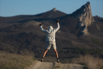 A man performs physical exercises against the backdrop of mountains. doing sports at sunset