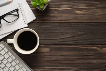 High overhead view photo of mug of strong beverage copybooks computer keyboard eyewear on dark wooden backdrop