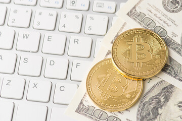 Above top close up view photo image of shiny golden bitcoin laying on pile stack of american usd paper banknotes with white keyboard buttons on the background