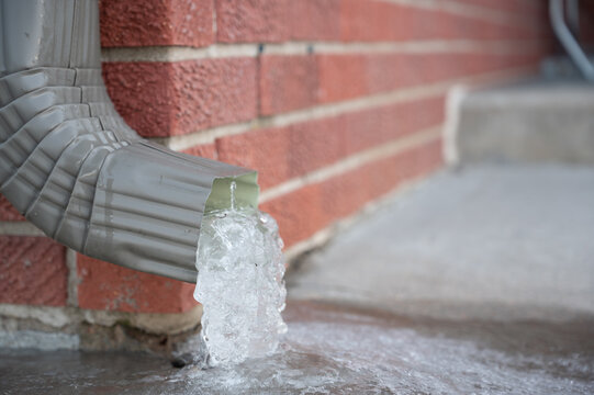 Metal downspout jammed with a frozen ice block